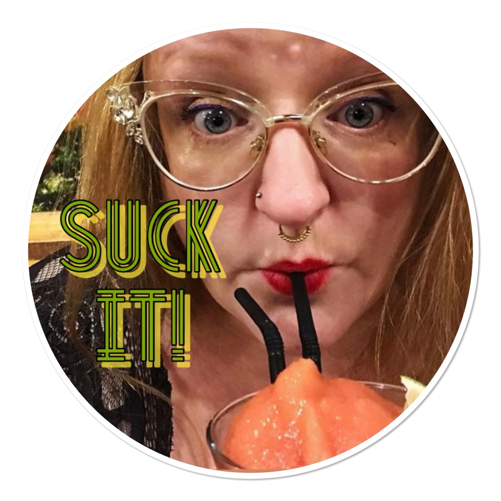 close up of red haired woman with retro glasses &  septum piercing sipping straw in iced drink 